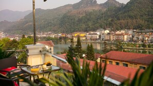 Une vue depuis un balcon donnant sur une ville, avec un lac et des montagnes en arrière-plan.