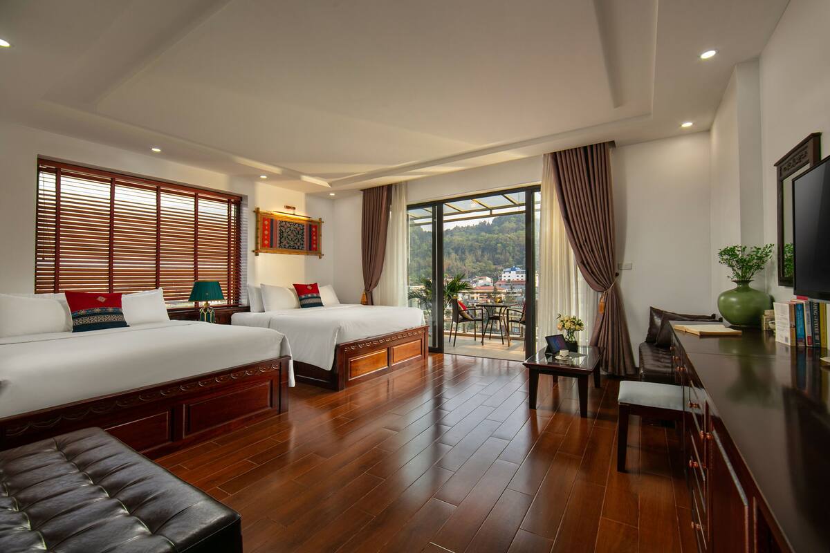 Een hotelkamer met twee bedden, een bank, een eettafel en een televisie.