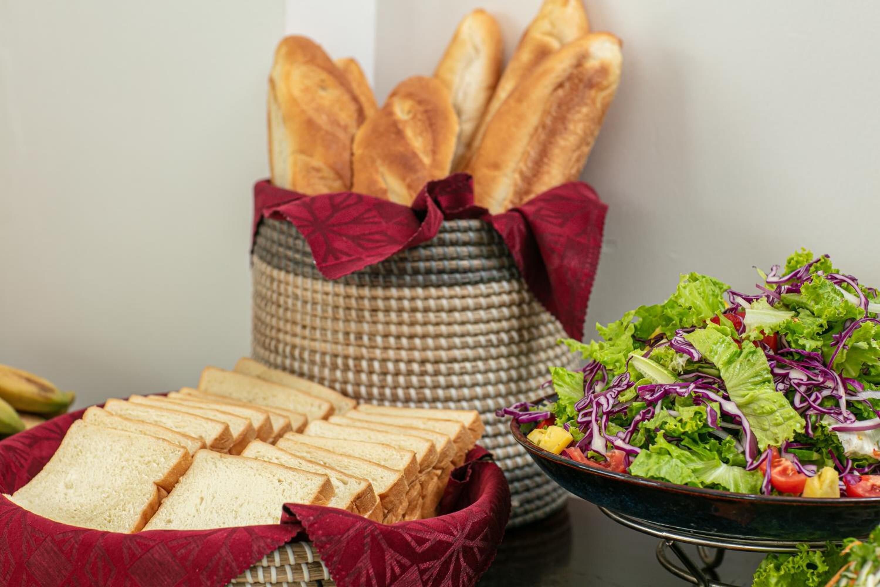 A table with sliced bread and a bowl of salad.