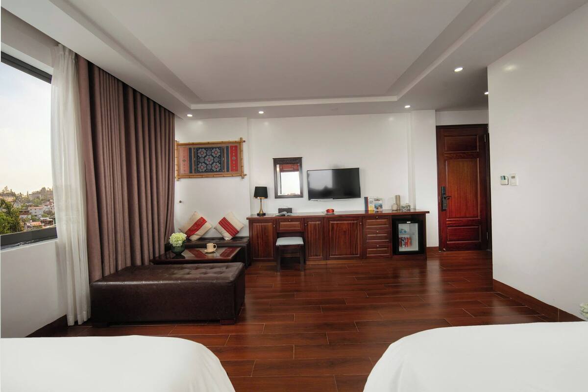 Een hotelkamer met een groot bed, een bank, een televisie, een bureau en uitzicht op de stad.
