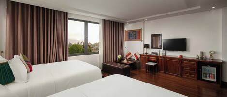 A hotel room with two beds, a desk, a television, and a minibar.