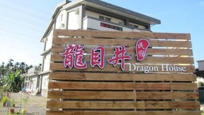 Un letrero de madera con caracteres chinos y las palabras en inglés 'Dragon House', que indica el nombre del establecimiento.