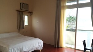 Una habitación con cama, ventana con cortinas y vista a un balcón.