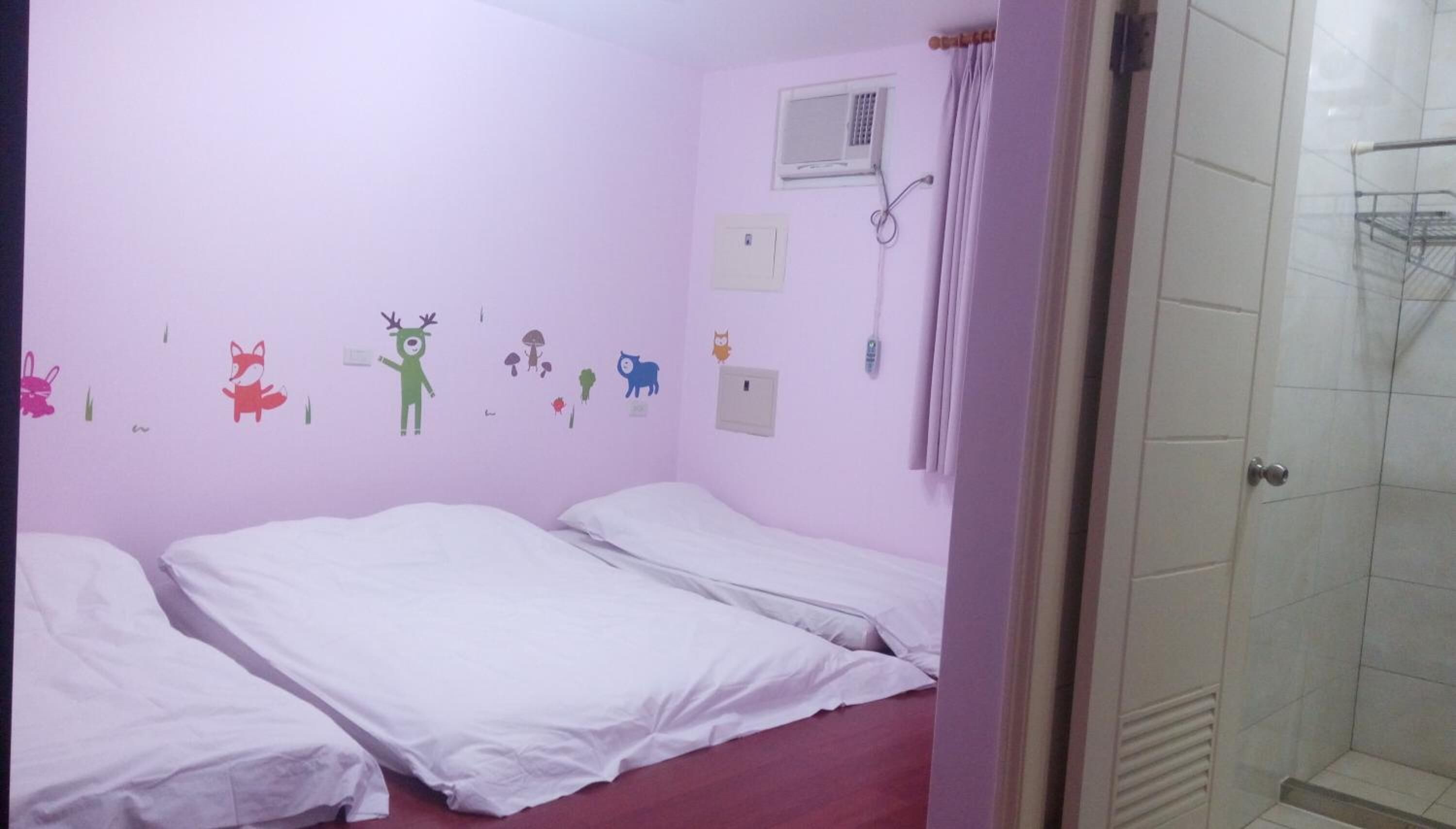 Une chambre avec deux lits, une douche et un mur décoré de dessins d’enfants.