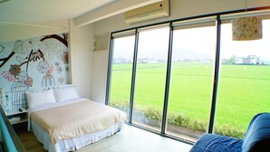 A bedroom with a large window, a bed, and a wall with a floral mural. - Lan Yang Resort Four Seasons (Dongshan)