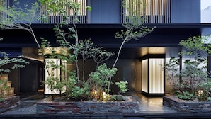 A modern building with a dark facade, vertical wooden slats, and a landscaped garden with various plants and a stone pathway. - Hotel Resol Kyoto Kawaramachi Sanjo (Kyoto)