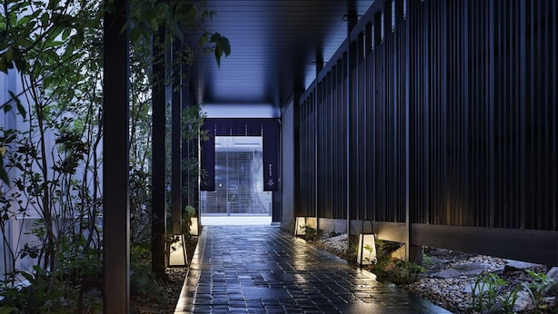 A pathway leading to a building entrance with a modern design, featuring a brick pathway and a metal fence on one side. - Hotel Resol Kyoto Kawaramachi Sanjo (Kyoto)