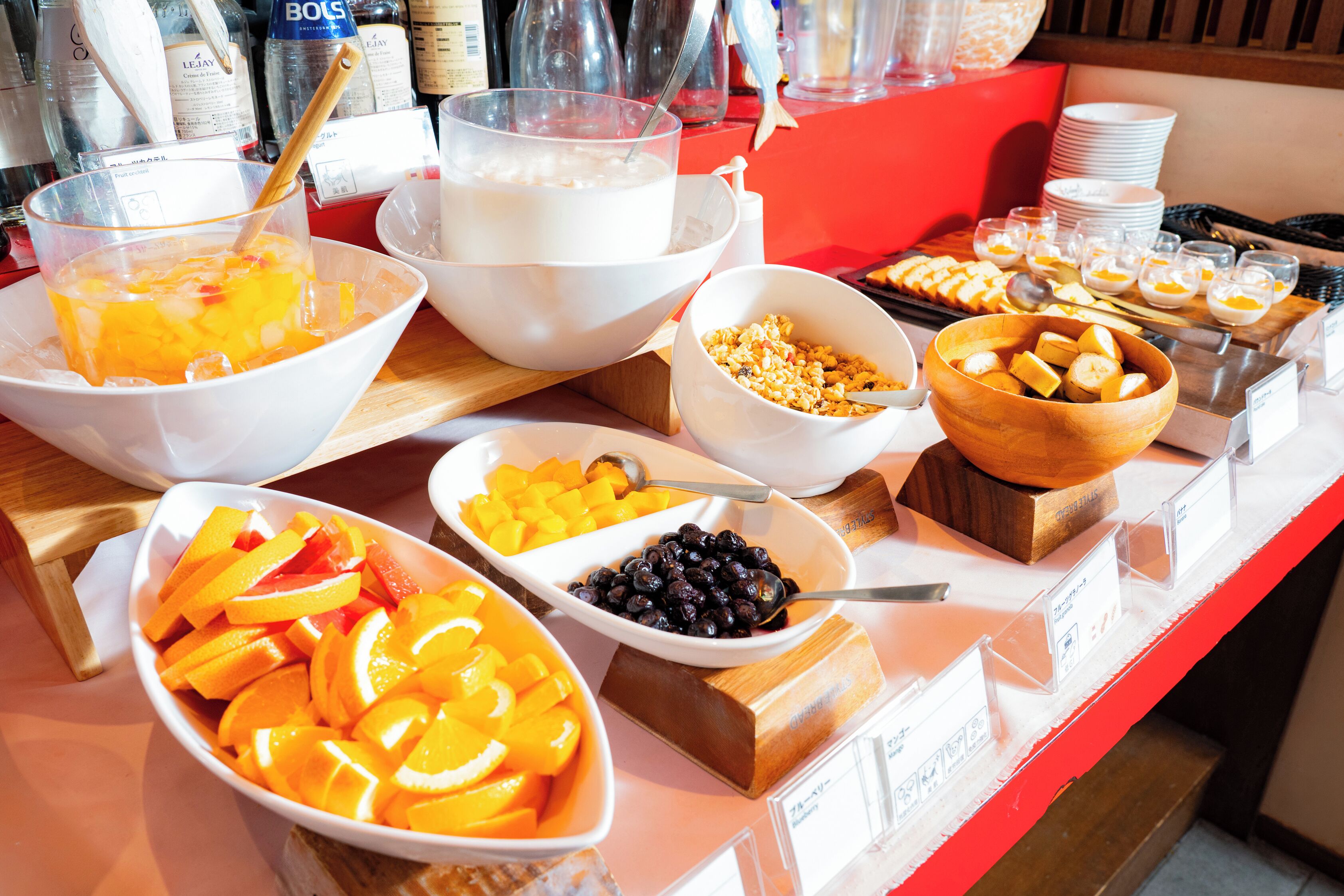 A buffet with various food items including fruits, yogurt, and cereal.