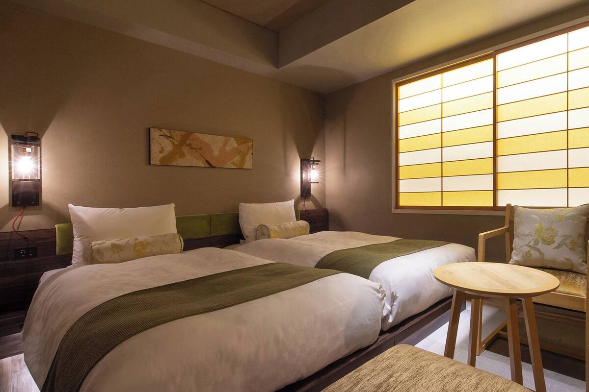 A hotel room with two beds, a chair, and a large window with a view.