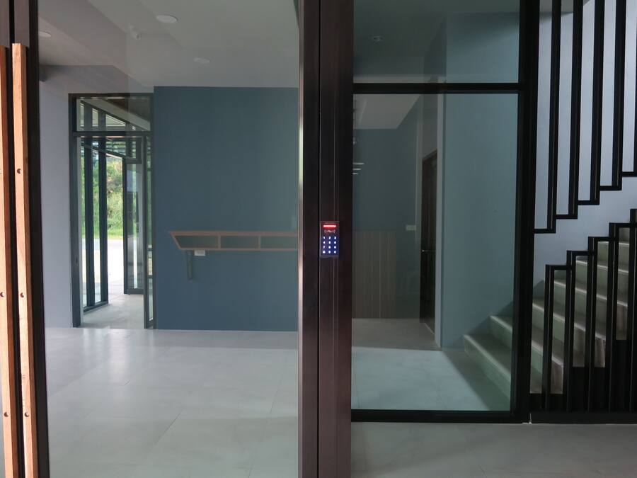 Vista interior de un edificio moderno con una escalera, un puerta de vidrio y un panel de control digital para el ascensor.
