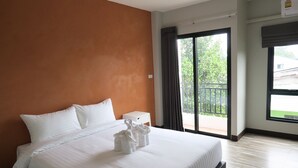 A hotel room with a large bed, a small bedside table, a window with a view of greenery, and a balcony. - Good Morning Hotel at TakuaPa (Takua Pa)