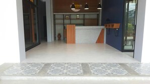 A reception area with a counter, a wooden cabinet, and a tiled floor. - Good Morning Hotel at TakuaPa (Takua Pa)