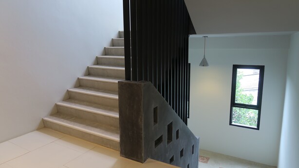 A staircase with a black railing and a window with a view of greenery. - Good Morning Hotel at TakuaPa (Takua Pa)