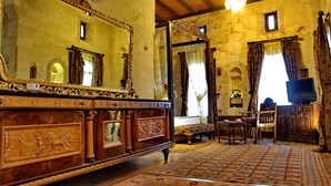 A room with a wooden ceiling, stone walls, a large mirror, a television, and a patterned rug. - Artuklu Kervansarayi - Special Class (Mardin)