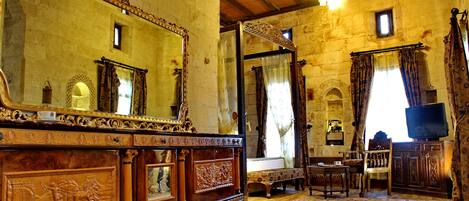A room with a wooden ceiling, stone walls, a large mirror, a television, and a patterned rug.