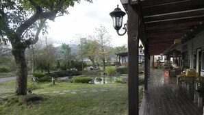A wooden deck with a pond, trees, and a scooter. - Zhuyuan Ju B&B (Yuanshan)