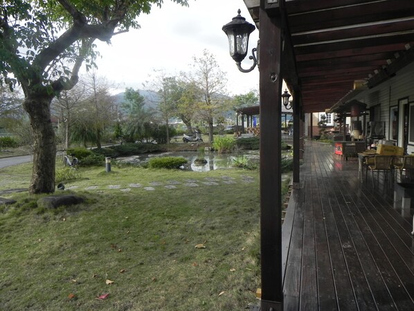 A wooden deck with a pond, trees, and a scooter. - Zhuyuan Ju B&B (Yuanshan)