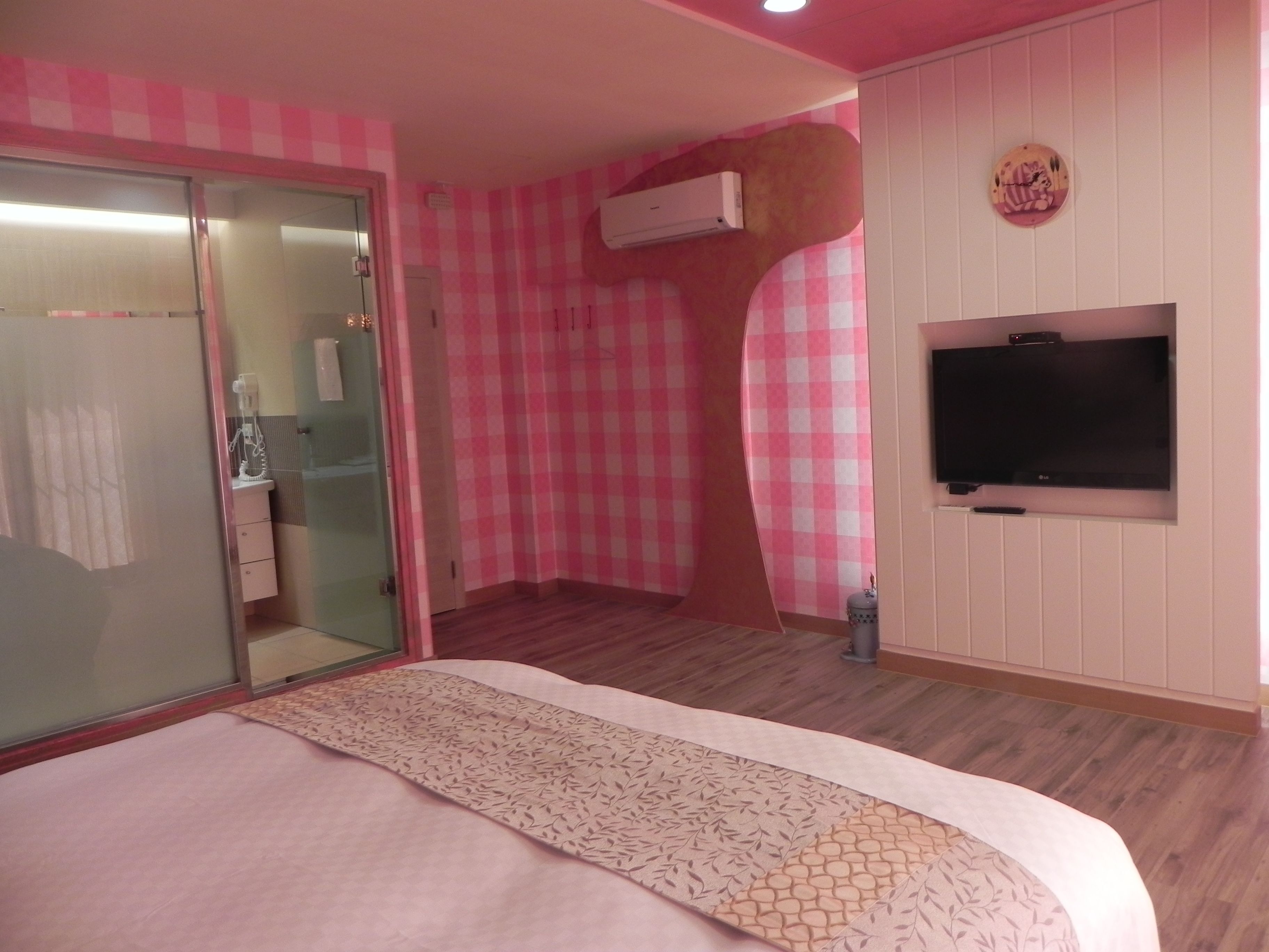 A bedroom with a bed, a television, and a bathroom with a glass door.