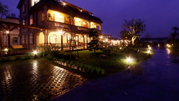 A large, two-story building with a balcony, illuminated by warm lights, and a paved pathway leading to it. - Zhuyuan Ju B&B (Yuanshan)