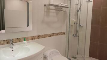 Un baño con lavamanos blanco, inodoro y cabina de ducha de vidrio.
