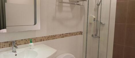 A bathroom with a white sink, toilet, and glass shower enclosure.