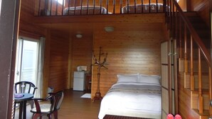 A wooden cabin with a loft bedroom, a dining area, and a small kitchen. - Zhuyuan Ju B&B (Yuanshan)