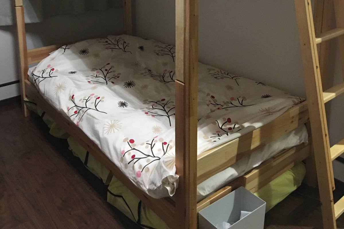 A bunk bed with a ladder, a pillow, and a floral-patterned bedspread.