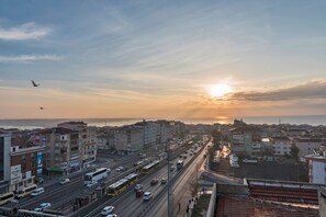 A cityscape with a sunset over a busy street, buildings, and a clear sky. - Land Park Hotel (Istanbul)
