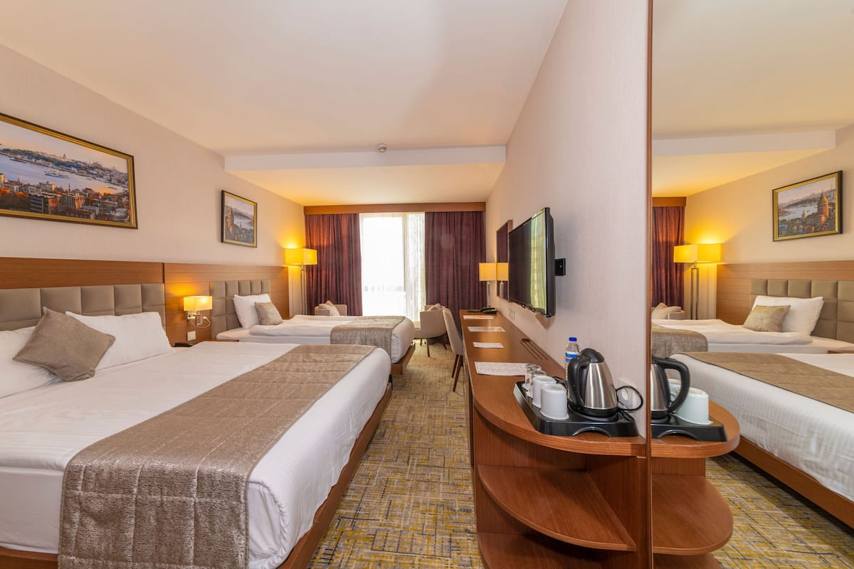 Una habitación de hotel con dos camas, un escritorio con cafetera y televisor.