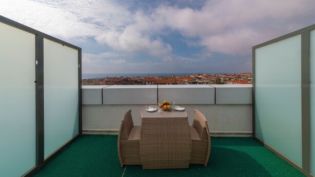 A balcony with a wicker table and chairs, a view of a cityscape, and a clear sky. - Land Park Hotel (Istanbul)