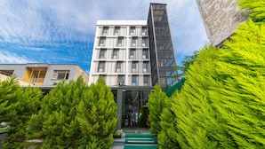 A modern building with a central entrance, surrounded by lush greenery and a clear sky. - Land Park Hotel (Istanbul)