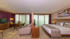 A hotel room with a bed, a desk, a chair, a television, and a painting on the wall. - Land Park Hotel (Istanbul)