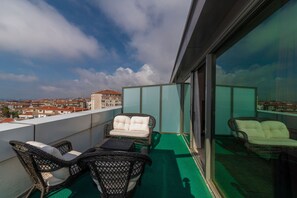 A balcony with wicker furniture, a green carpet, and a city view. - Land Park Hotel (Istanbul)