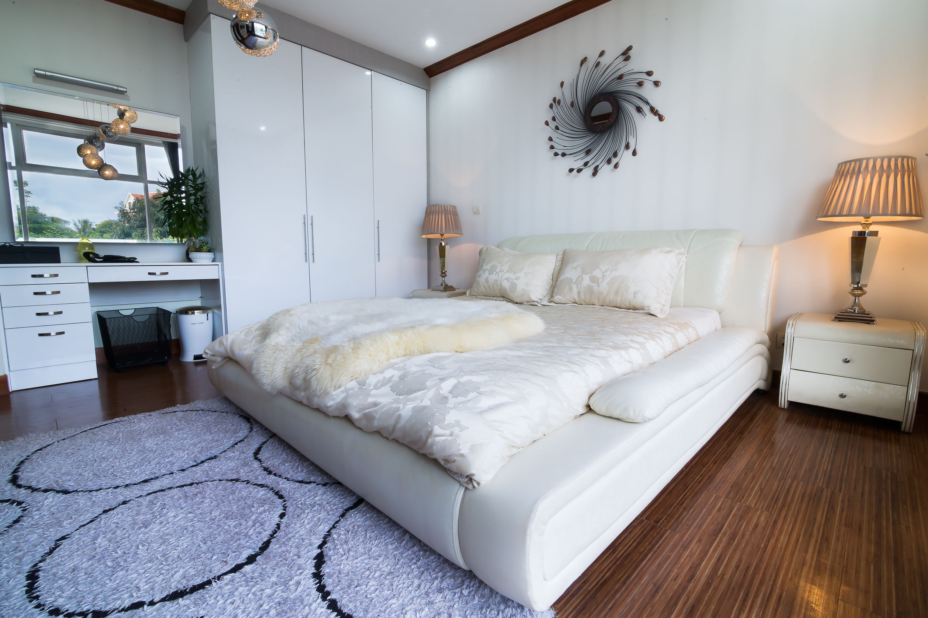 A modern bedroom with a large bed, a desk, and a wardrobe.