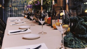 A table set for a meal with candles, wine glasses, and a vase of flowers.