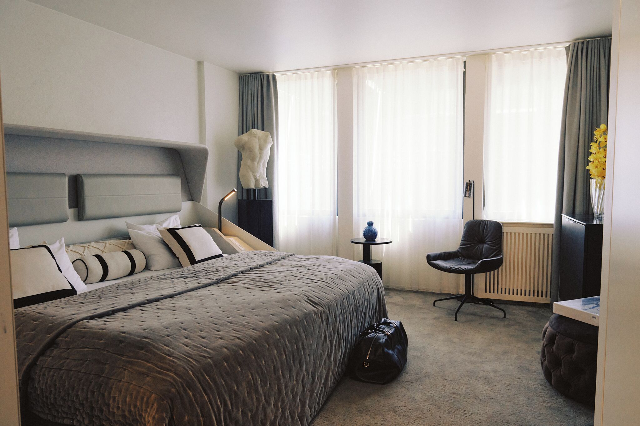 Een hotelkamer met een bed, een stoel, een klein tafeltje en een radiator.