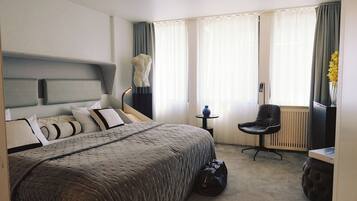 Una habitación de hotel con cama, una silla, una mesita y un radiador.