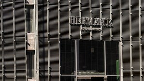 Un edificio con un letrero que dice "HERMAN K" y una persona montando una bicicleta al frente.