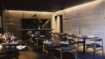 Un restaurante con paredes de madera, mesas dispuestas con copas de vino y sillas.