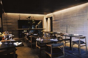 A restaurant with wooden walls, tables set with wine glasses, and chairs. - Boutique Hotel Herman K (Copenhagen)