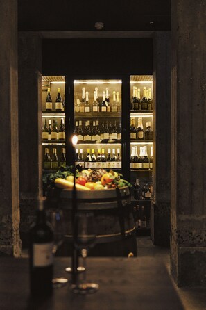 Un espace bar avec des étagères remplies de bouteilles de vin et un présentoir de fruits.