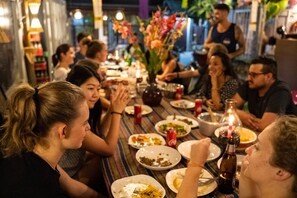 A group of people dining at a restaurant with a variety of dishes on the table and a bottle of beer. - Thailand wow Guesthouse - Hostel - Adults Only (Chiang Mai)
