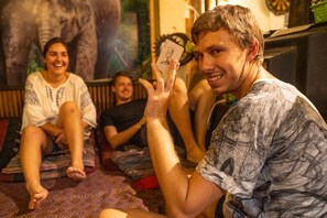 A person holding a playing card in a room with a large poster of an elephant on the wall. - Thailand wow Guesthouse - Hostel - Adults Only (Chiang Mai)