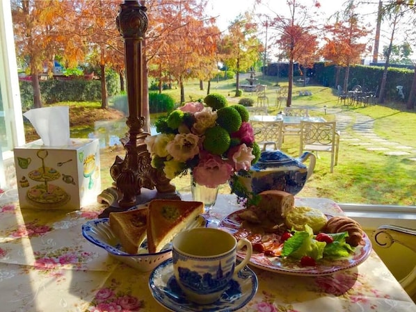 A table set with a floral tablecloth, a vase of flowers, and various food items. - England Castle B&B (Wujie)