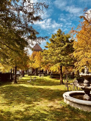 A park with a stone building, a fountain, and a picnic area. - England Castle B&B (Wujie)
