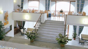 A hotel lobby with a staircase, seating area, and large windows.