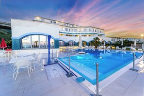 A rooftop pool with white chairs and tables, a glass balustrade, and a building with balconies and a terrace. - Hotel Poseidon (Belvedere Marittimo)