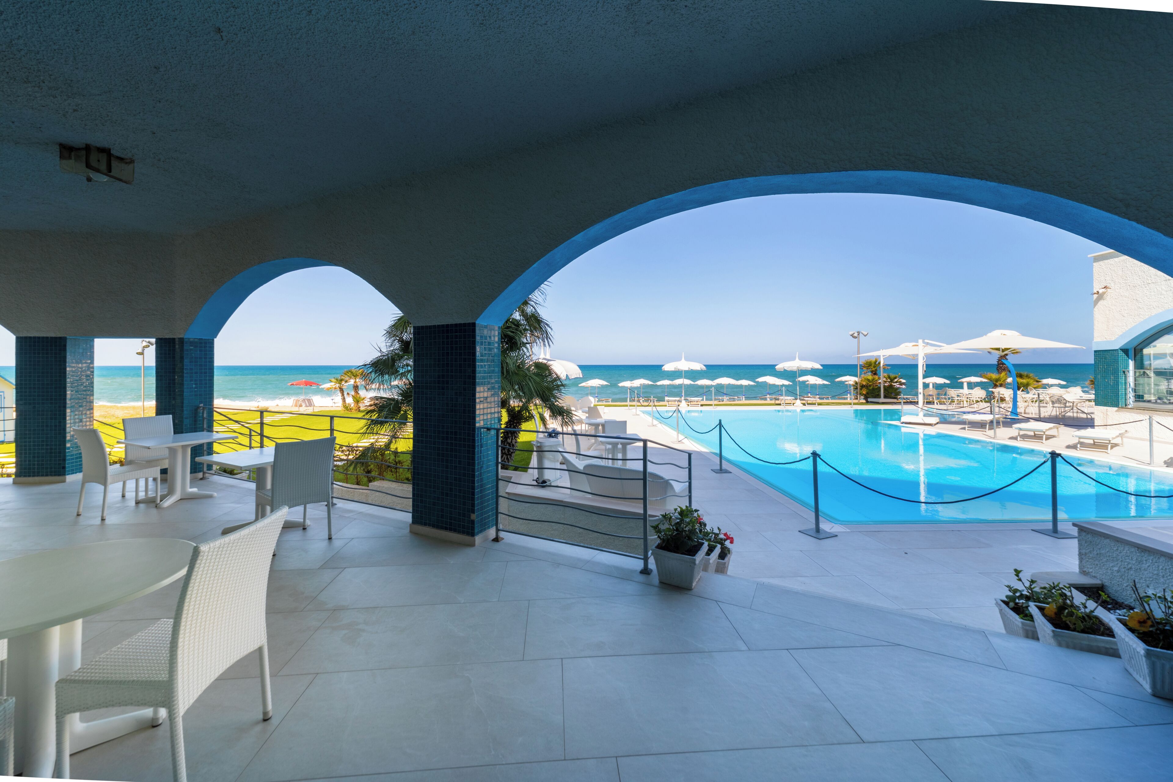 Zona de piscina con vista al océano, sillas de descanso y un comedor.