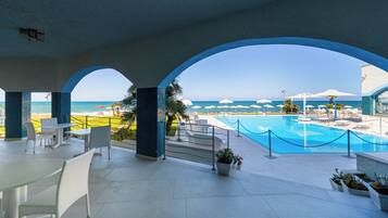 Zona de piscina con vista al océano, sillas de descanso y un comedor.