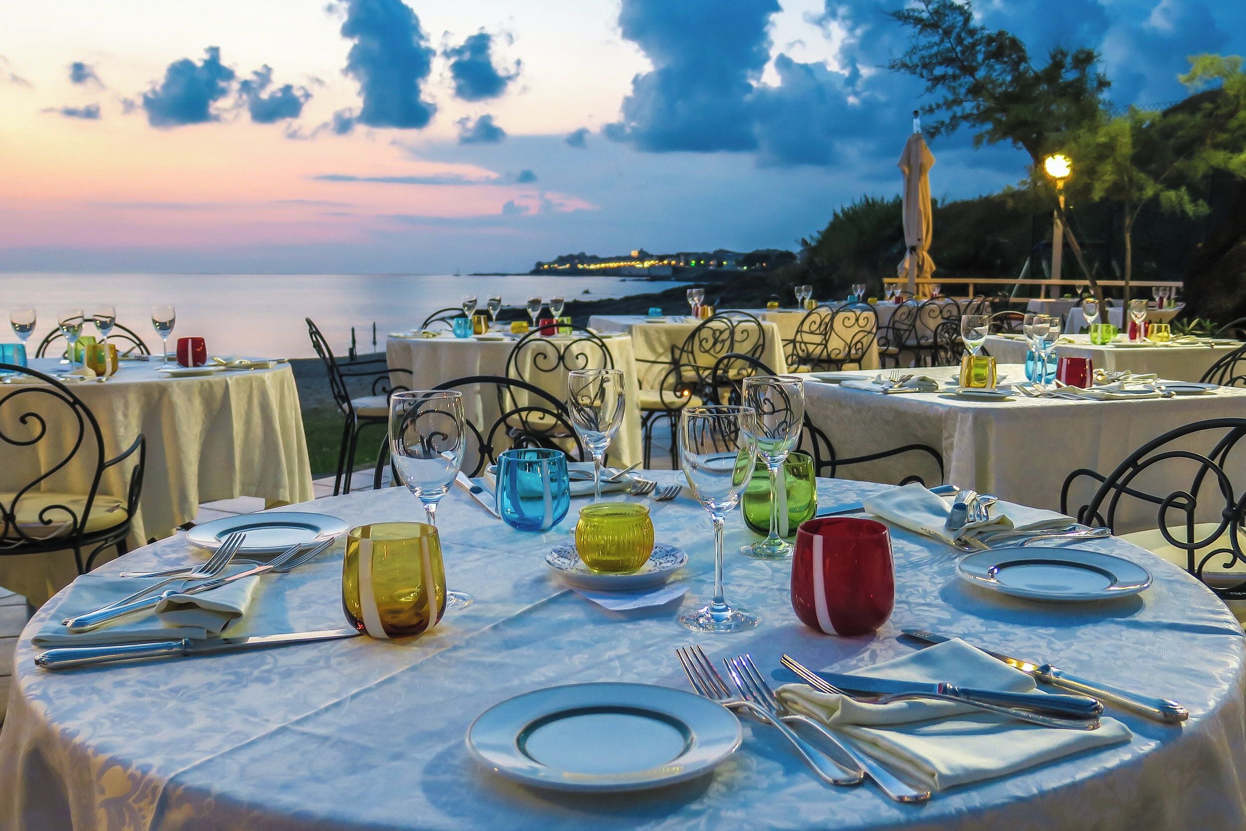 Mesa lista para comer con vista al mar al atardecer.